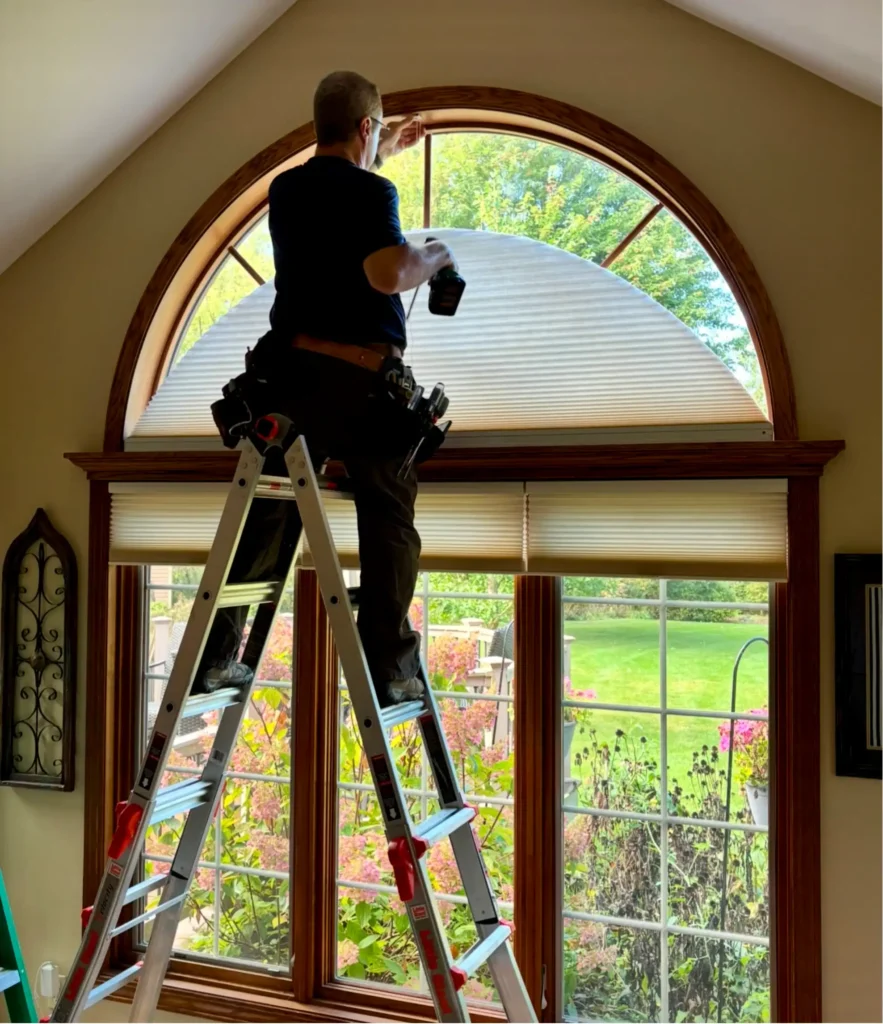 Installer fitting honeycomb shades on an arched window