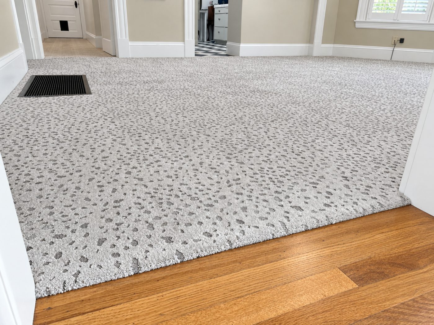 Patterned gray and white carpet meeting wood-look luxury vinyl plank