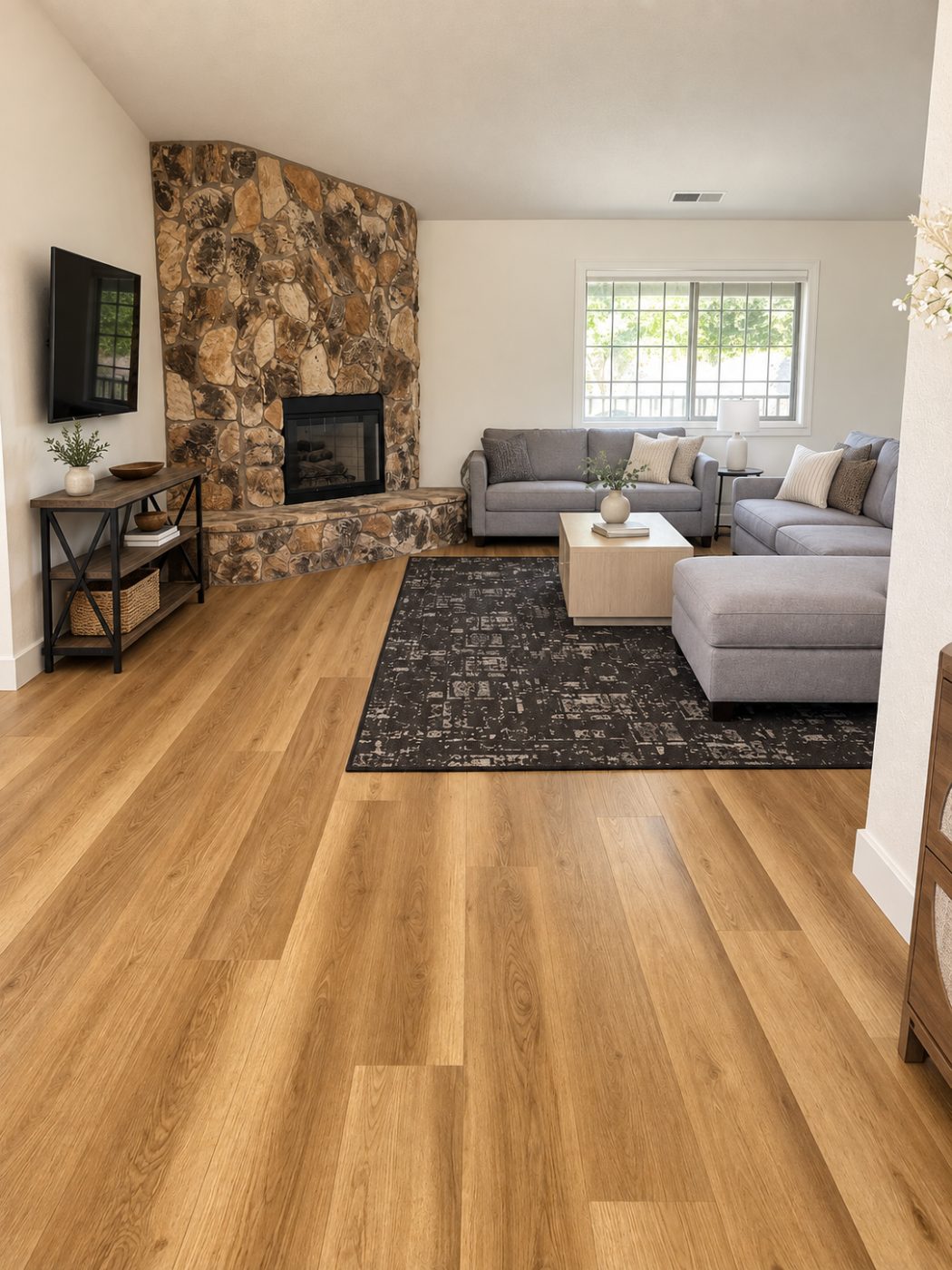 Warm wood-look luxury vinyl plank in a living room with a stone fireplace