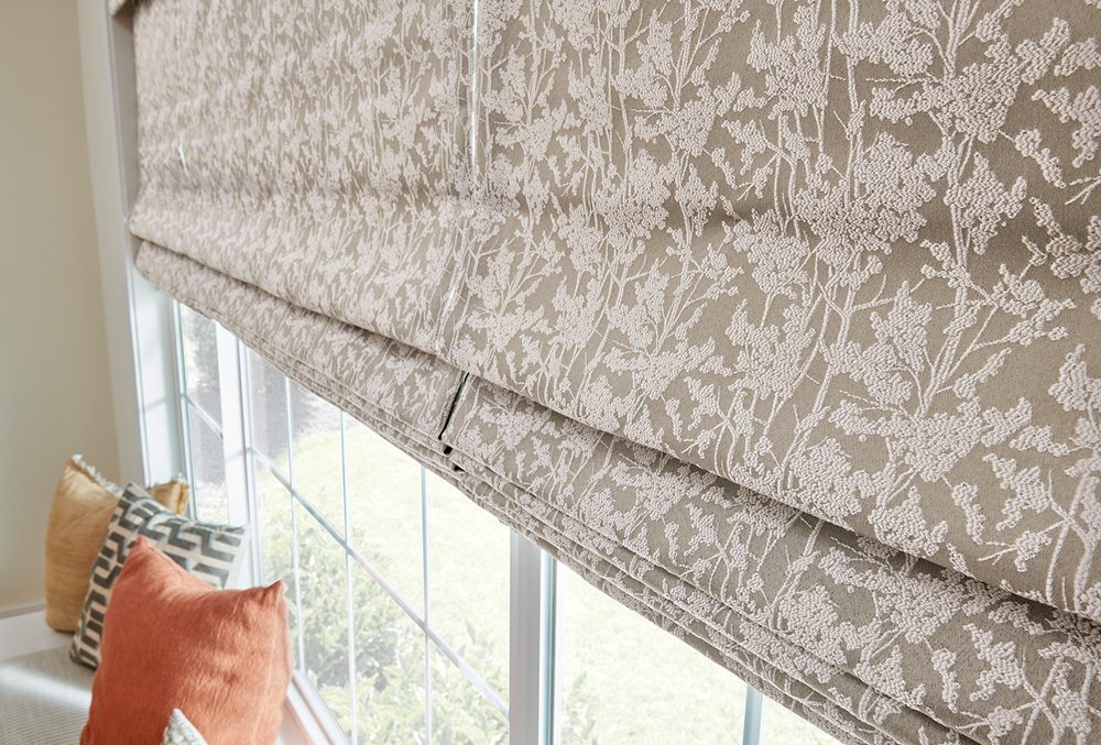 Patterned Graber soft Roman shade on a window above a bench